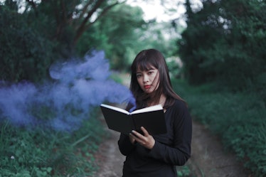 Portrait Asian woman in black dress holding a little notebook in hands, witch-hunt before Halloween ...