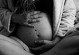 Woman holding a pregnant belly in bed (black and white photo)