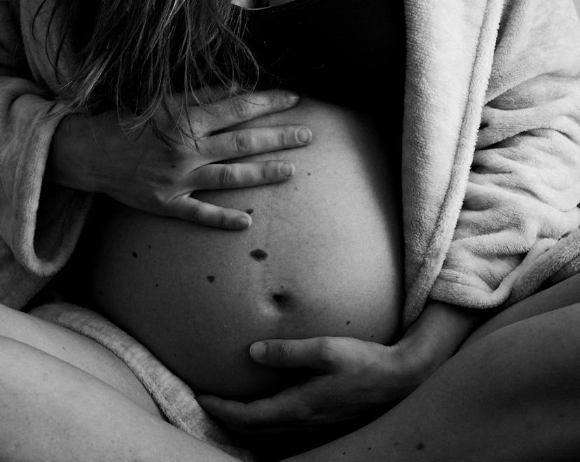 Woman holding a pregnant belly in bed (black and white photo)