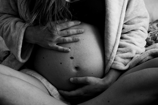 Woman holding a pregnant belly in bed (black and white photo)