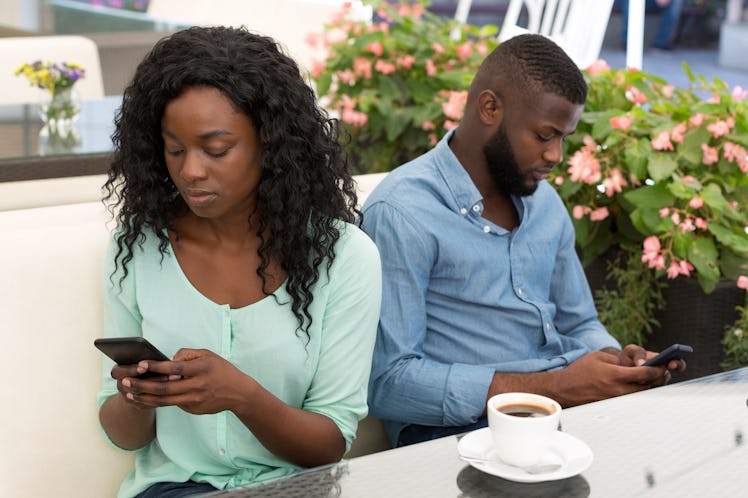 Smarthone addiction. Obsessed couple with their mobile phones ignoring each other sitting in cafe