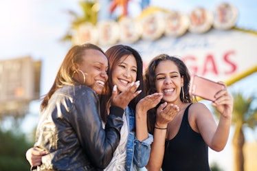 all girl group of friends having fun taking selfies in front of welcome to las vegas sign