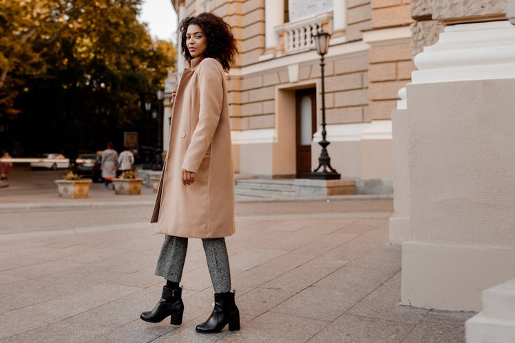 Fashion  full length  image of elegant  black woman in stylish luxury beige coat and velvet sweater,...