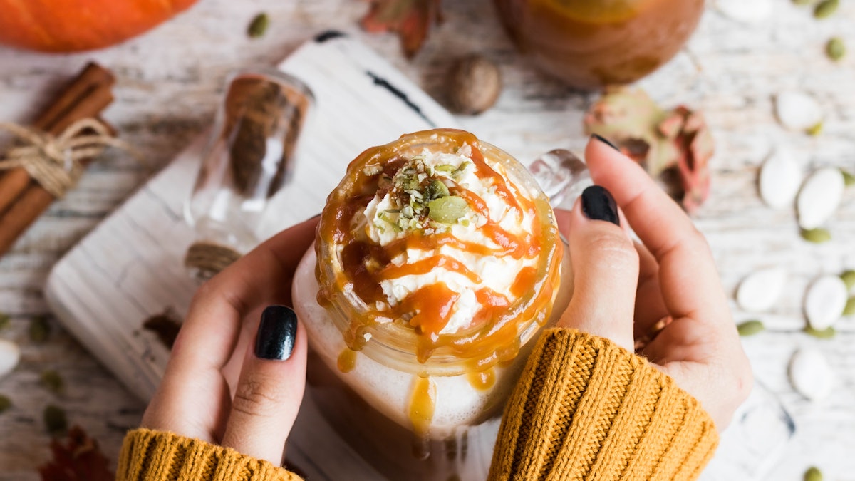Spicy pumpkin latte with spices and a cap of whipped cream decorated with salted caramel and crushed...