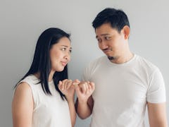 Sulk and reconcile Asian couple lover in white t-shirt and grey background.