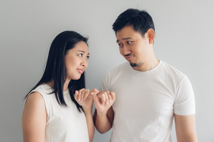 Sulk and reconcile Asian couple lover in white t-shirt and grey background.