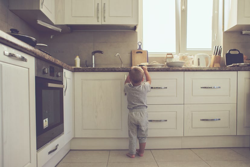 2 years old child standing on the floor alone in the kitchen, casual lifestyle photo series in real ...