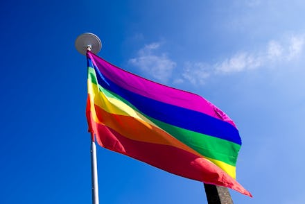 Rainbow flag on blue sky background.LGBT flag ,gay flag,gay pride.Gay flag Uk.Gay flag covering vert...
