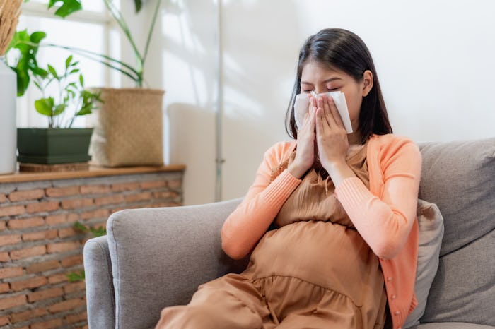 Young Asian pregnant woman blowing her nose