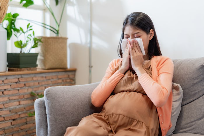 Young Asian pregnant woman blowing her nose