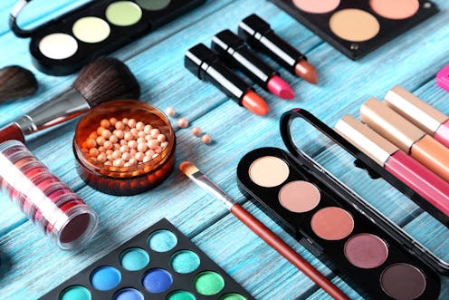 Makeup brush and cosmetics on blue wooden table