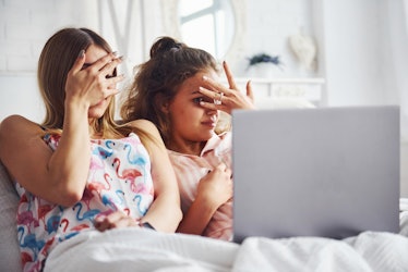Two friends watching a scary movie on their laptop in bed may be in need of captions for Halloween m...