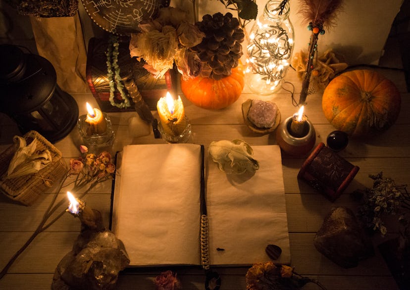 An old book with clean pages and burning candles, witchcraft, natural crystals and skull, pumpkin, w...