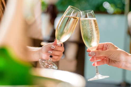 two girls clink glasses of champagne on a beautiful summer terrace. sparkling champagne glasses. clo...