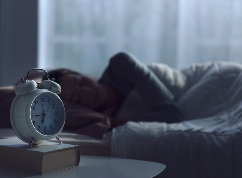 Serene woman sleeping in her bed and alarm clock in the foreground. While researchers say that adequ...