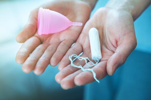 gynecological health, menstruation products to chose, female hands holding pink silicone menstrual c...