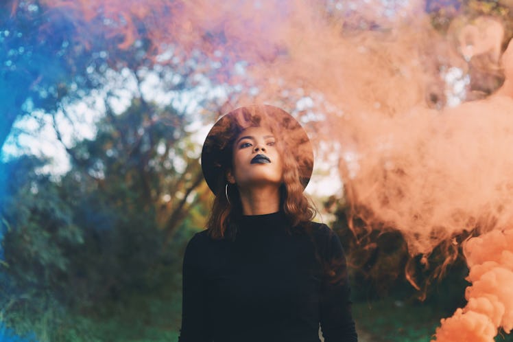 Beautiful woman in black dress standing in forest in Halloween concept.