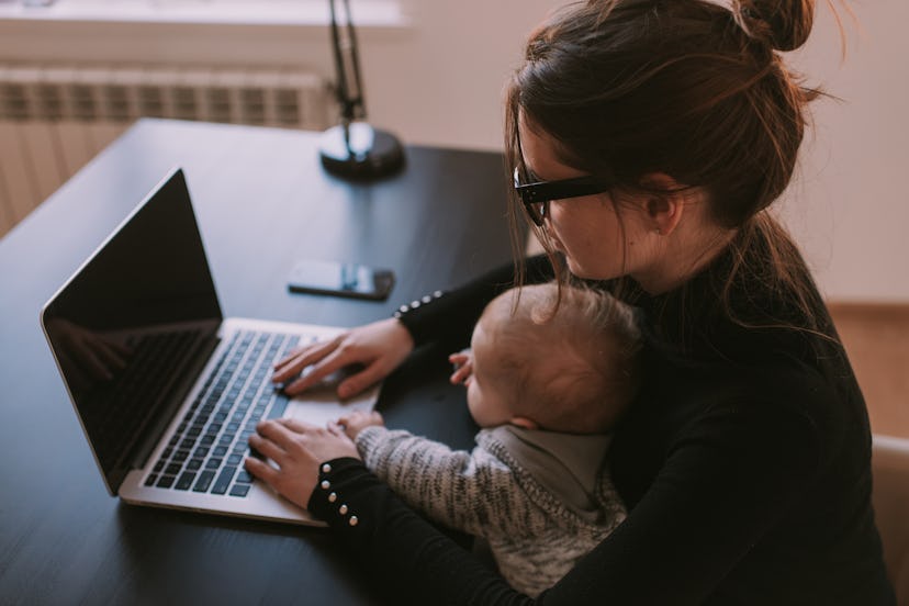 A mother working on laptop with child. 