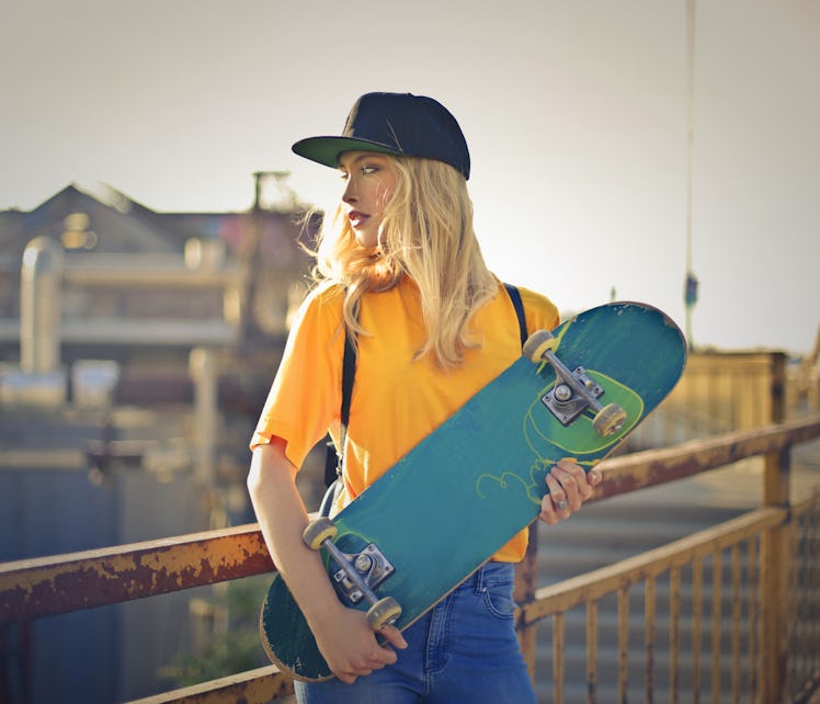Young woman with her North Node in Aries holding a skateboard.