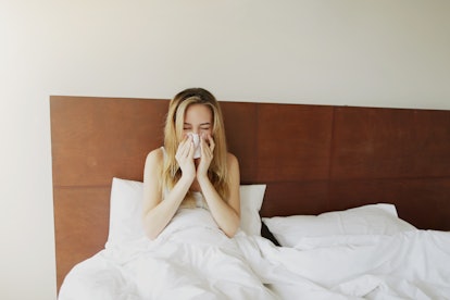 Female sick Woman sneezes in white bed with napkin Sunlight , get cold outside. Concept of pills med...
