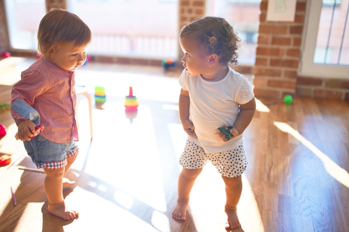 Adorable toddlers playing around lots of toys at kindergarten