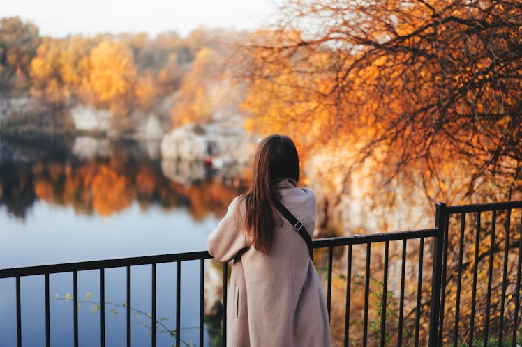 Autumn girl standing backwards and watching nature.