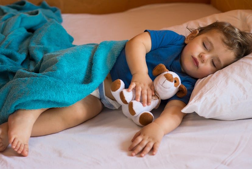 Cute baby boy sleeping on the bed at home with toy. 