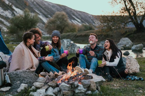 Camping time for a big group of friends sitting beside the fireplace and enjoying the time together ...