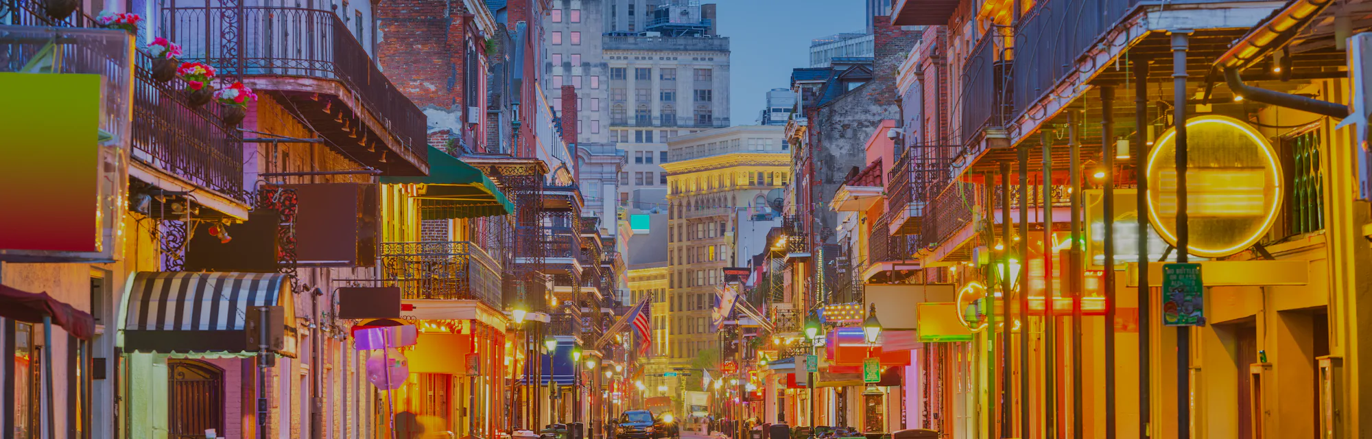 Bourbon St, New Orleans, Louisiana, USA cityscape of bars and restaurants at twilight.