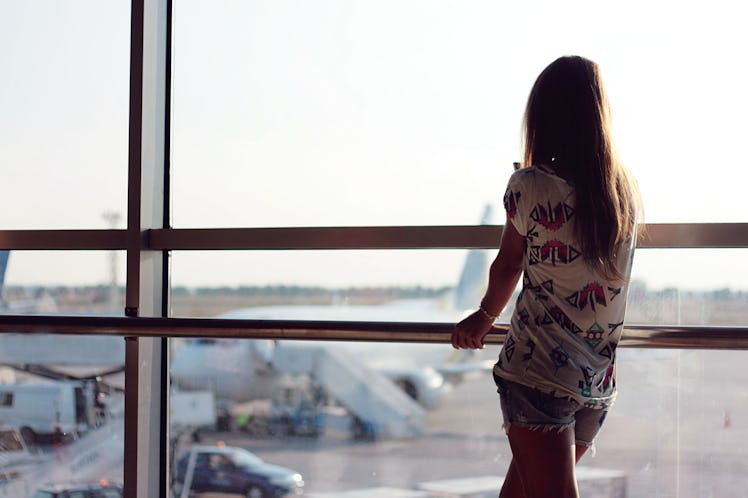 A young woman looks out at planes from an airport window. The chances of a plane crash are extremely...