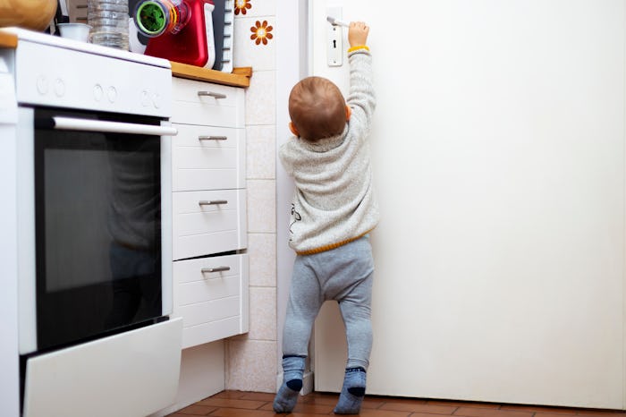 A little cute boy wants to open a door in the room. Portrait of a baby trying to reach a door-handle...