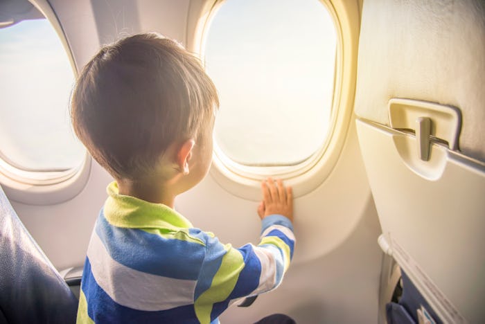 asian boy looking aerial view of sky and cloud outside airplane window while sitting on airplane sea...