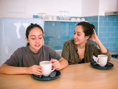Teen sisters talking while they are having breakfast in the kitchen