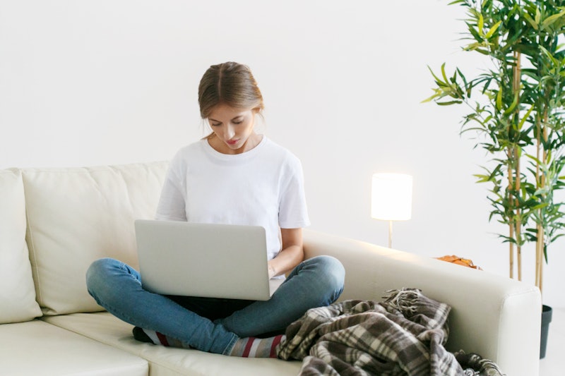 Woman with laptop home sitting sofa using internet