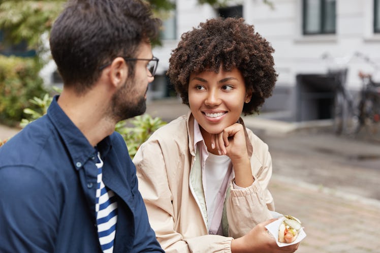 Photo of mixed race tourist enjoy lively communication, discuss traditions of their countries, eat f...