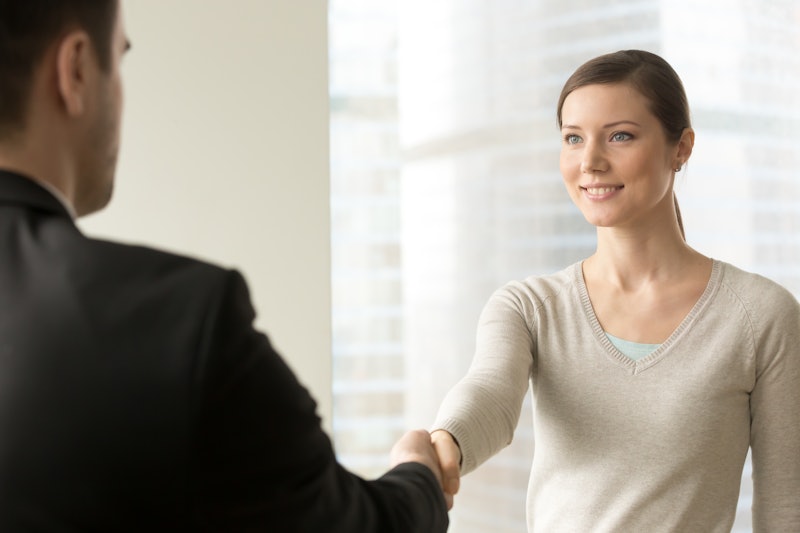 Attractive millennial woman handshaking with man in business suit. Confident young businesswoman wel...