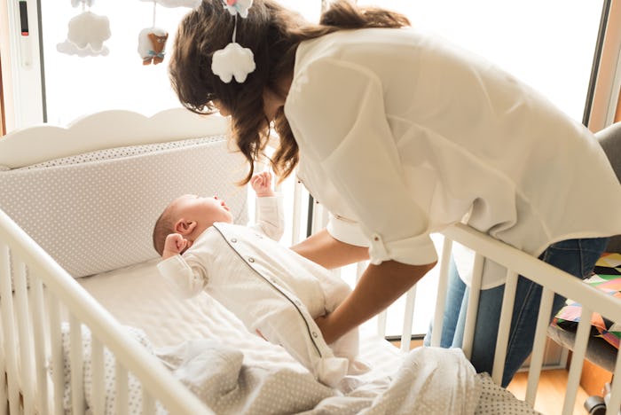Mother putting baby to sleep at the crib