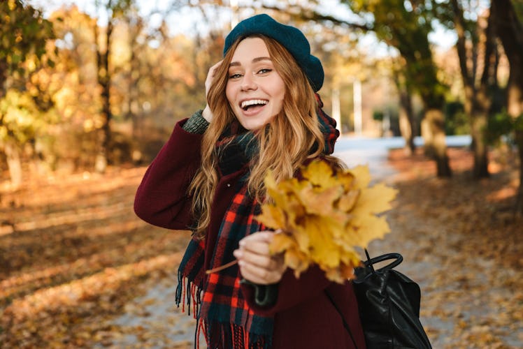 Cheerful young girl with long brown hair wearing autumn coat, walking at the park