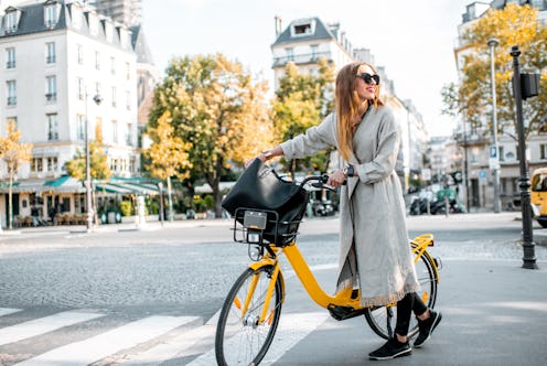 Portrait of a young stylish woman with yellow bicycle on the street in Paris