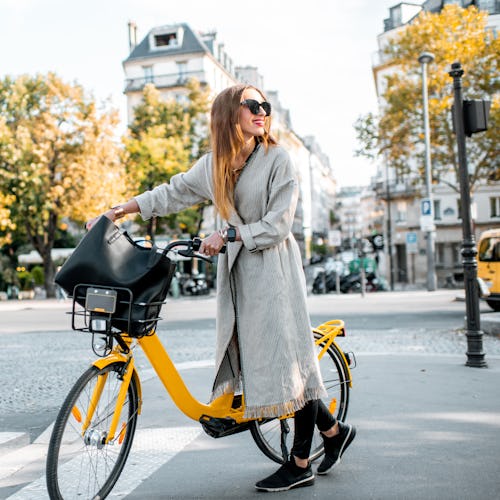 Portrait of a young stylish woman with yellow bicycle on the street in Paris