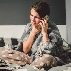 respiratory diseases and home remedies. young woman sick with cold sitting bedroom on bed holding th...