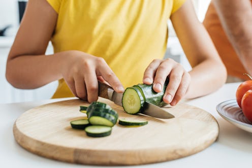cropped shot of girl cutting cucumber with knife