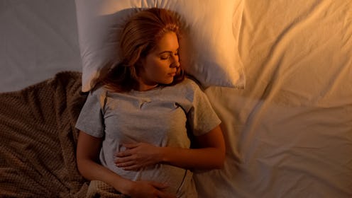 Young woman sleeping in white comfortable bed with brown blanket, top-view