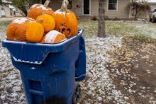 Giant pumpkins sitting in a trash dumpster waiting for garbage pickup after Halloween. Concept for c...
