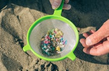 Detail of hands holding colander with microplastics on the beach