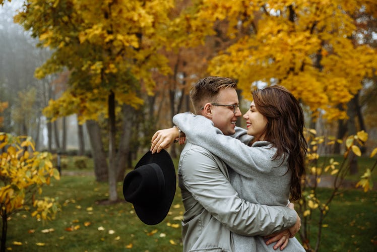 Loving couple in stylish casual wear hugs in the park in the autumn season. Autumn. Golden autumn. G...