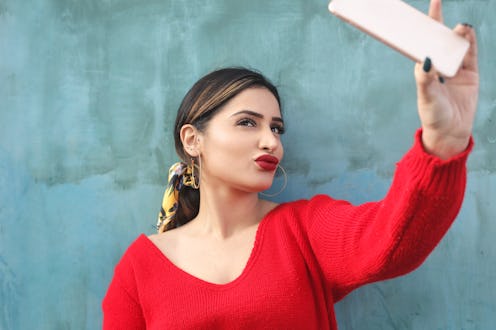 Girl taking a selfie with her smart phone. Instagram is removing filters associated with plastic sur...