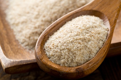 Heap of psyllium husk in wooden spoon and bowl on table. Psyllium husk is a natural remedy for const...