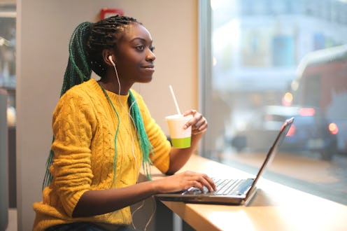 Girl having lunch in a bar, listening to a podcast and using her laptop