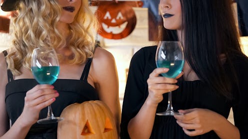 Witches holding cocktails and having fun at Halloween party, creepy celebration
